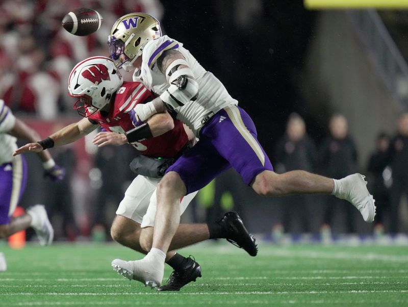 Washington linebacker Zach Durfee (5) forces a fumble by Wisconsin quarterback Carter Smith (5) during the third quarter of their game Saturday, November 8, 2025 at Camp Randall Stadium in Madison, Wisconsin. Wisconsin beat Washington 13-10. Wisconsin recovered the ball.