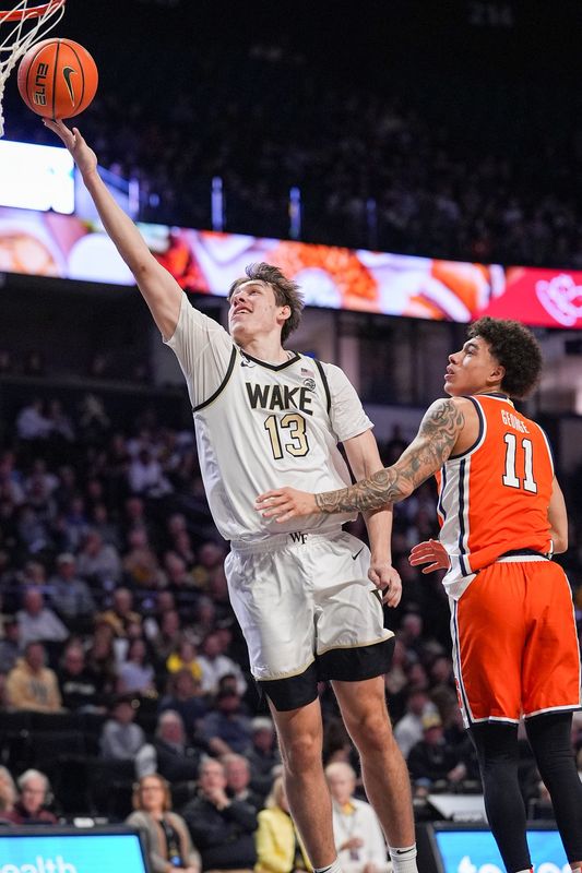 Feb 28, 2026; Winston-Salem, North Carolina, USA; Wake Forest Demon Deacons forward Cooper Schwieger (13) makes a lay up past Syracuse Orange guard Naithan George (11) during the first half at Lawrence Joel Veterans Memorial Coliseum. Mandatory Credit: Jim Dedmon-Imagn Images
