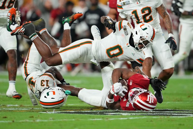 Jan 19, 2026; Miami Gardens, FL, USA; Miami Hurricanes defensive back Keionte Scott (0) tackles Indiana Hoosiers running back Kaelon Black (8) during the first half of the College Football Playoff National Championship game at Hard Rock Stadium. Mandatory Credit: Kirby Lee-Imagn Images