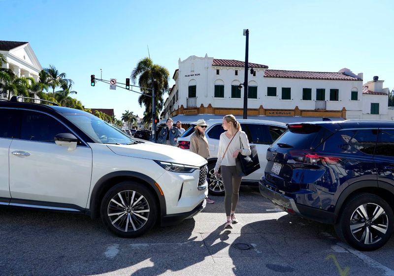 People walk in the crosswalk at the intersection of South County Road and Royal Palm Way amid gridlock, as vehicles try to travel off the island while South Ocean Boulevard is closed next to President Donald Trump's Mar-a-Lago Club, on Feb. 6 in Palm Beach.
