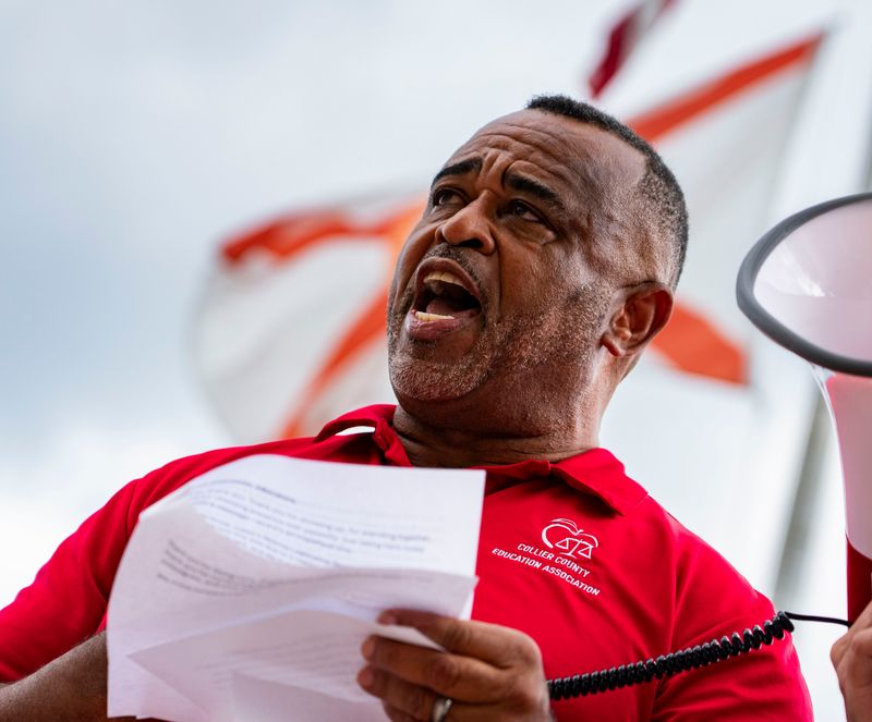 CCEA President Ken Mouton speaks as the flag of Florida waves behind him during a rally at the Collier County Public Schools Admin Center in Naples, Fla., on Monday, April 27, 2026. The attendees were originally there to attend the public hearing to discuss the impasse with the Collier County Education Association and school board. It was canceled due to a board member having a medical emergency, according to the CCPS website.