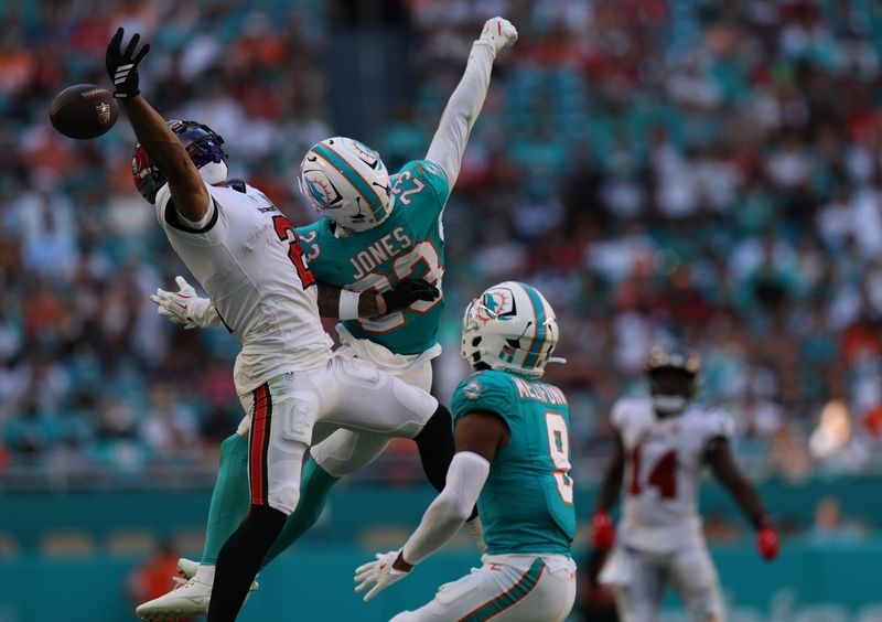 Dec 28, 2025; Miami Gardens, Florida, USA; Tampa Bay Buccaneers wide receiver Emeka Egbuka (2) misses a pass while under pressure from Miami Dolphins cornerback Jack Jones (23) and safety Ifeatu Melifonwu (9) during the fourth quarter at Hard Rock Stadium. Mandatory Credit: Nathan Ray Seebeck-Imagn Images