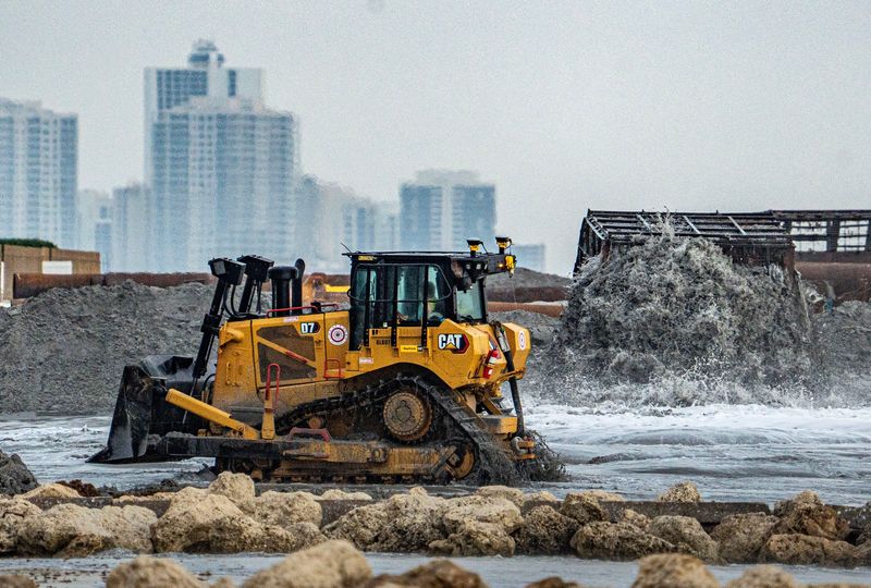 The driver of a Caterpillar D7 Dozer earth-moving machine pushes sand on April 30 as beach restoration efforts continue in Palm Beach.