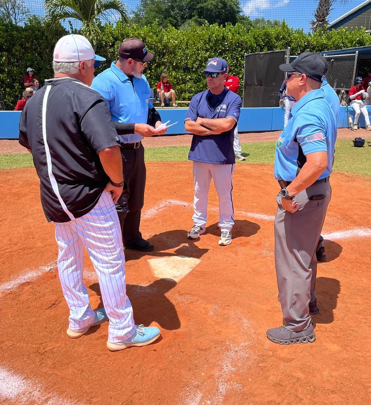 St. John Paul II coach Pete Graffeo, left, and Chaminade-Madonna coach Jerry Albert, center, meet with the umpires before a Region 4-2A semifinal game on May 1 in Boca Raton. The coaches did not shake hands.