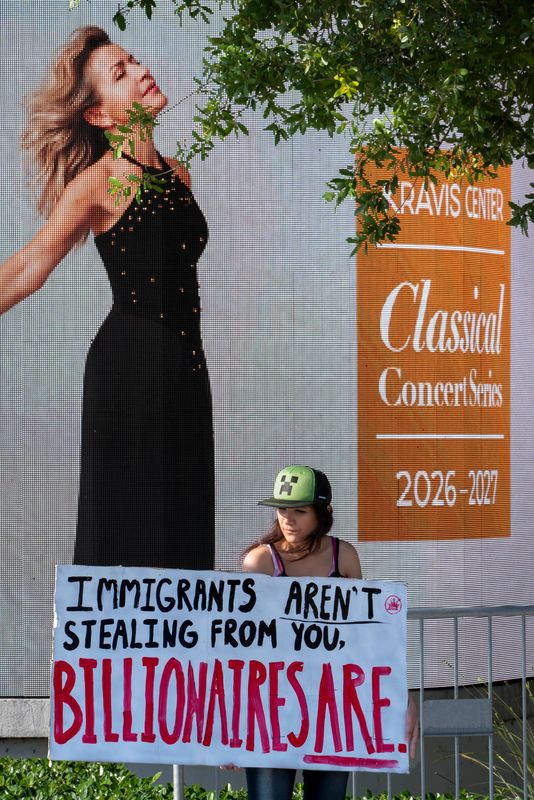 Protesters holds signs before President Donald Trump's speech to the Forum Club of the Palm Beaches at the Kravis Center on May 1, 2026, in West Palm Beach, Florida.