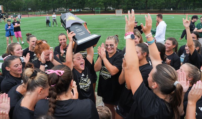 Jacksonville University midfielder Isabella Porazzo (12) hoists the 2026 Women’s Lacrosse Tournament Championship trophy into the air while celebrating with teammates after the women’s Jacksonville University lacrosse team defeated the University of Delaware Blue Hens 16-11 in the ASUN Championship game at Rock Stadium Saturday May 2, 2026 in Jacksonville, Fla. [Doug Engle/Florida Times-Union]