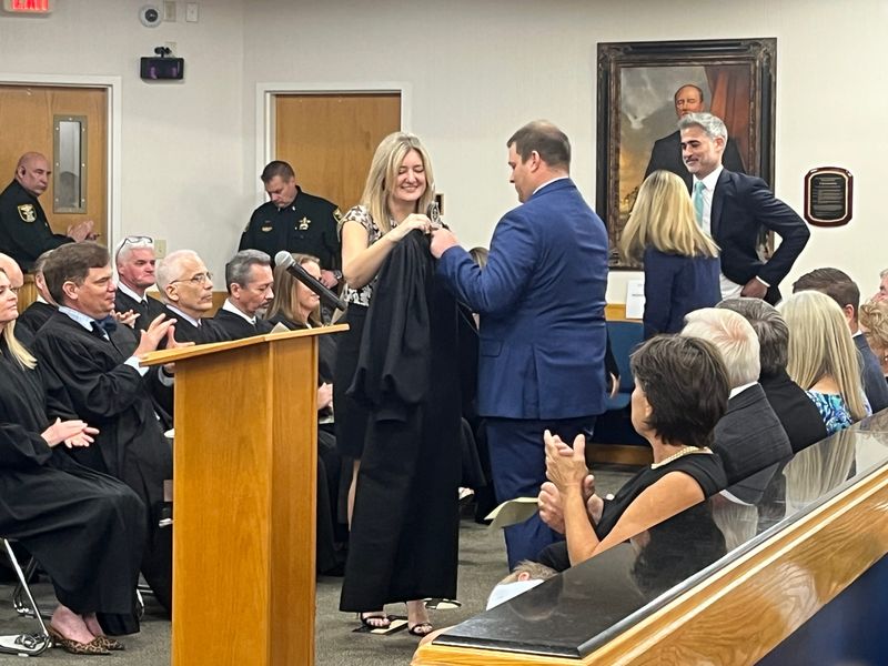 Tony Mish, right, helps his wife Circuit Judge Katherine Donaldson Mish into a new black robe after she took the oath of office during a ceremony on May 1, 2026 at the Martin County Courthouse, in Stuart following her appointment by Gov. Ron DeSantis in December.
