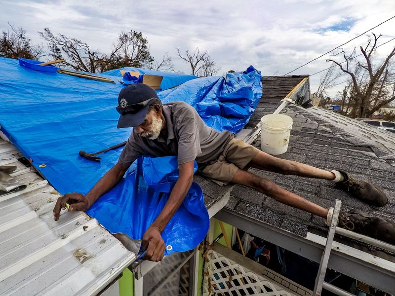 Willie Clark helps cover a friend's home who had to go to work in Springfield, Florida after damage from hurricane Michael on October 25, 2018. [RICHARD GRAULICH/pbpost.com]