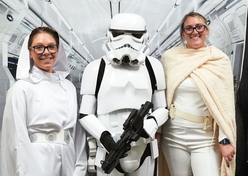 Nichole Buckles (left) and Stephanie Tolson, both with Flagler County, pose together in "Star Wars"-themed outfits with a storm trooper before the start of the May 4, 2026, "Star Wars"-themed marriage ceremony at the Kim C. Hammond Justice Center in Bunnell.