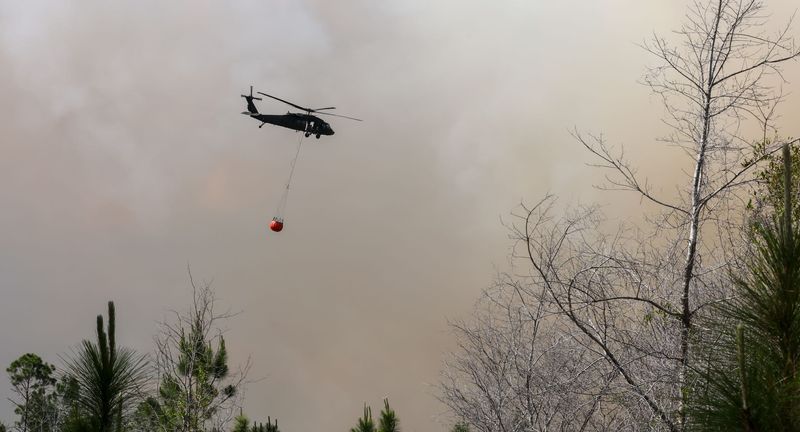 A helicopter brings water as the Florida Forest Service battles a large wildfire on May 4 near South County Road 325 and Southeast County Road 346 in Hawthorne. Crews also deployed ground equipment and aircraft to help contain the fire.