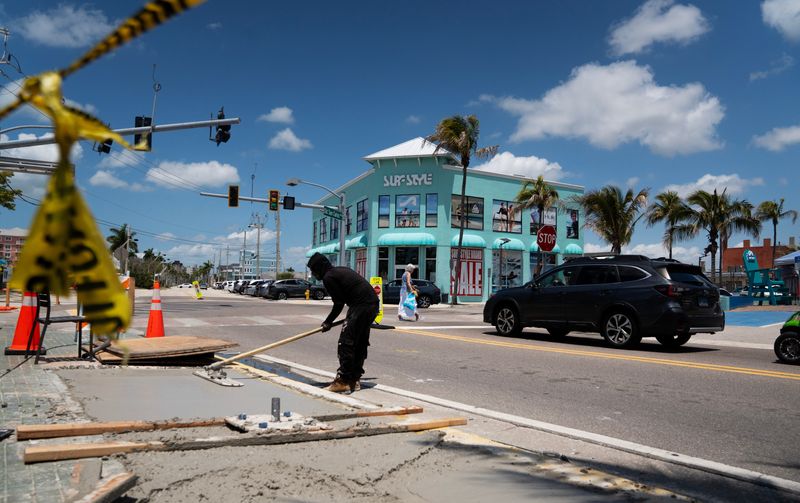 A worker replaces a portion of sidewalk near Times Square on Fort Myers Beach on Monday, May 4, 2026. A new traffic light is getting replaced at the intersection Old San Carlos and Estero Boulevard. The area is still recovering from Hurricane Ian.