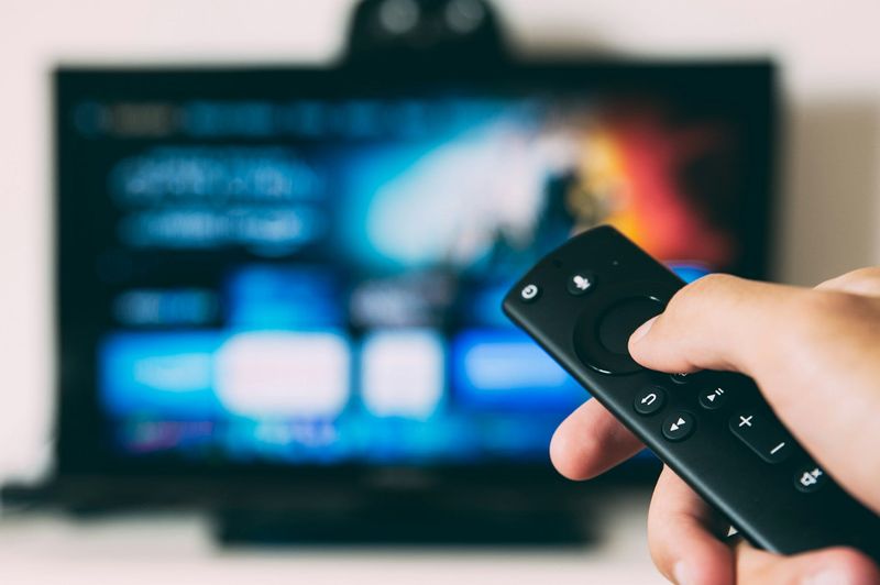 A person holding a remote control while navigating content on a television screen.
