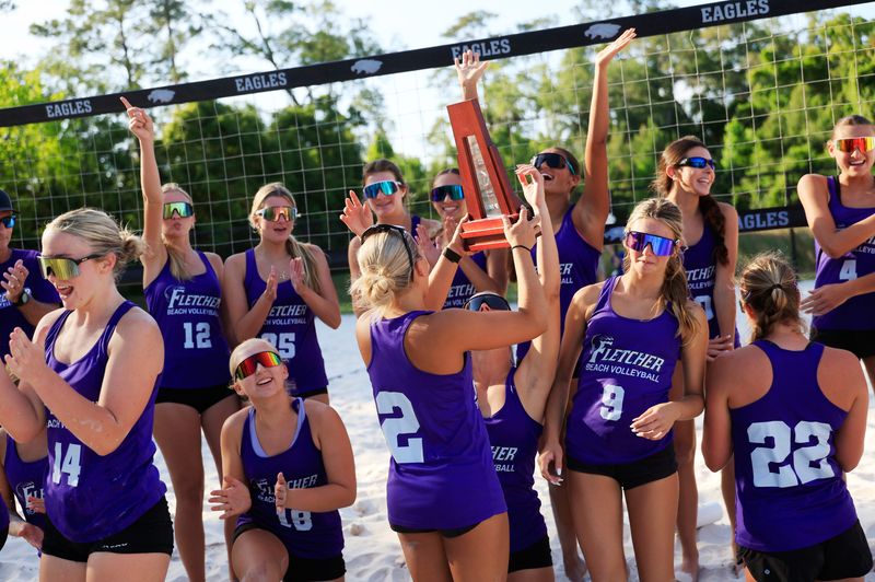 Fletcher's Leila Brummel (2) holds up the championship trophy as teammates cheer after an FHSAA Region 1-3A girls beach volleyball final at Episcopal School’s Knight Sports Campus, Tuesday, May 5, 2026, in Jacksonville, Fla. The Fletcher Senators blanked the Lake Brantley Patriots, not yielding a single set, 2-0, across five paired (doubles) teams.
