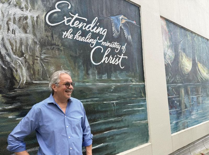 Artist Courtney Canova stands in front of his mural at AdventHealth DeLand.