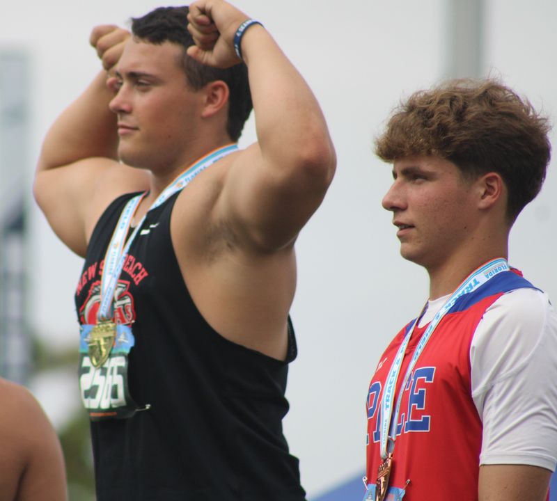 New Smyrna Beach's Brison Sullivan flexes his muscles on the podium after setting a boys javelin meet record during the FHSAA Class 3A track and field championships in Jacksonville on May 8, 2026.