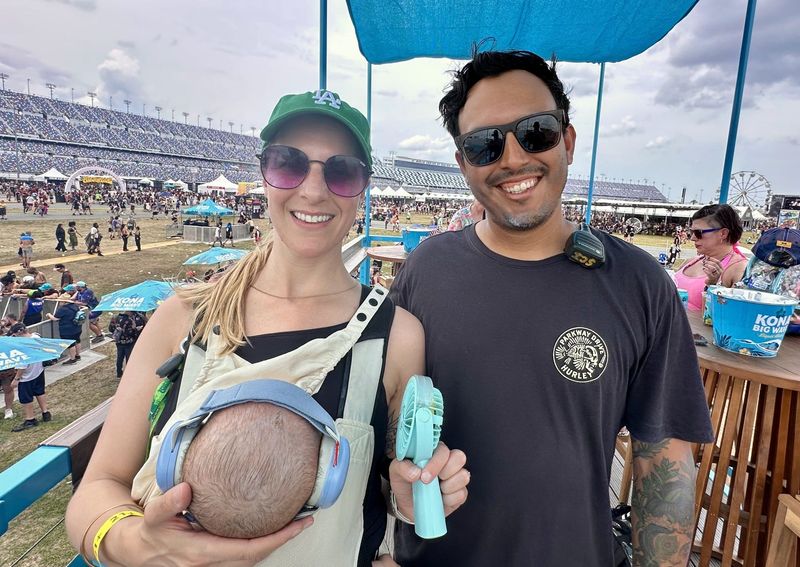 Natalie and Michael Valenzuela pose with their 5-month-old son Eric (with noise-canceling headphones) at Welcome to Rockville in Daytona Beach on May 9, 2026. Natalie Valenzuela, who visited the festival from California, said she opted to spend her first Mother's Day with her husband, an electrician who was working the festival.