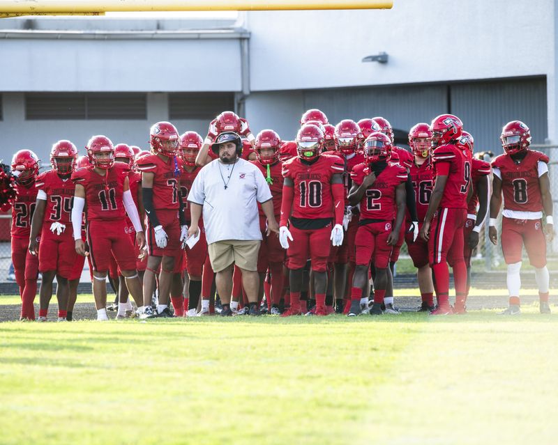 Head coach Hector Clavijo leads Santaluces onto the field at the start of a 2023 game against Pahokee.