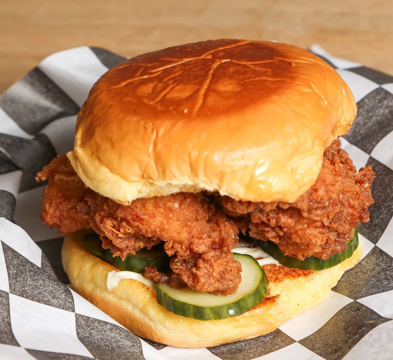The new Buffalo chicken sandwich at Hard Pressed Burgers features Gremolata, pickles, mayo, Blue Cheese, garlic aioli with shredded parmesan cheese.