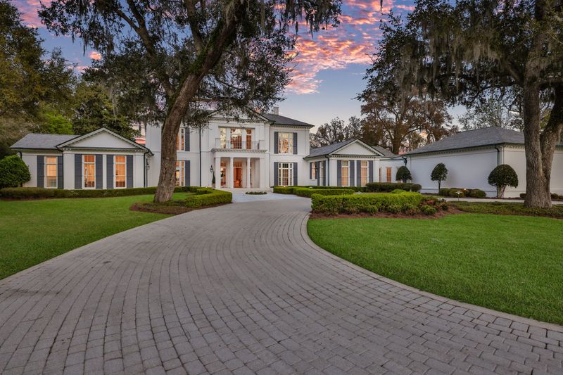 The front of the home is approached by a long, winding driveway.