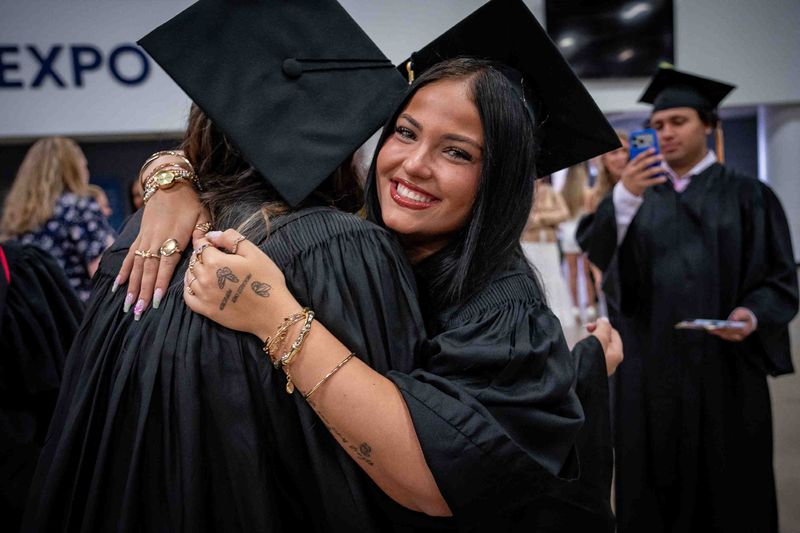Stefani Lefkowitz greets a classmate as Olympic Heights Community High School students prepare for graduation ceremonies at the South Florida Fairgrounds and Expo Center in unincorporated Palm Beach County, Fla., on May 15, 2025.
