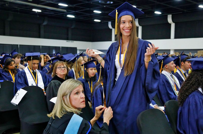 Beverley Colletti, the Boca Raton Community High School AICE coordinator, fixes the gown zipper for Annabella Federico prior to Saturday's graduation ceremony. Boca Raton Community High School graduation ceremony at the South Florida Fairgrounds on May 16, 2026, in suburban West Palm Beach, Florida.
