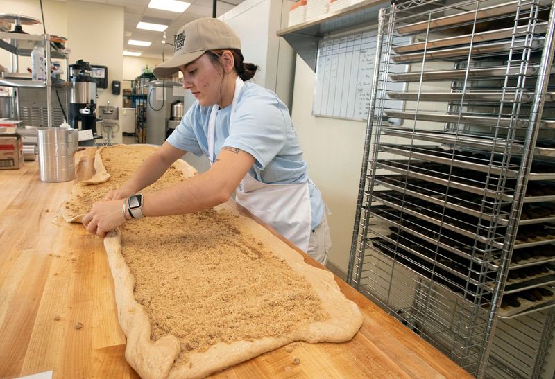 Michelle Moore handmakes cinnamon rolls at Great Harvest on May 21, 2026. Great Harvest will open at the Savoy Market on May 22, 2026. The new downtown bakery will offer handmade bread, pastries, sweets, and sandwiches, all made fresh every day.