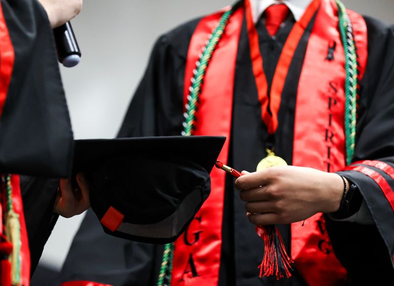 Graduates Matthew Dennis, left, and Austin Mulcahy honor classmate Christopher Brooks by moving a tassel from left to right during the South Fork High School Class of 2026 commencement ceremony, May 21, 2026, in Martin County. Brooks, 18, died in a crash the morning of graduation while on his way to graduation practice near the school.