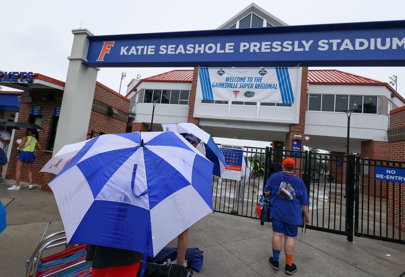 Damp fans wait for the gates to be open before game 2 of the super regional of the NCAA Division 1 softball championship at Katie Seashole Pressly Stadium in Gainesville, FL on Saturday, May 23, 2026. Morning showers forced a rain delay of the game and delay of letting fans into the stadium. [Alan Youngblood/Gainesville Sun]