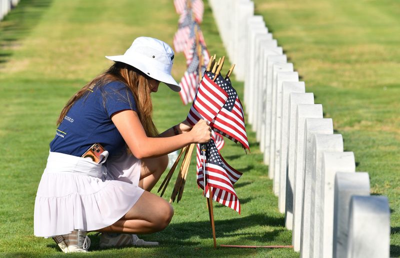 Allysa Mijares places flags by headstones at Cape Canaveral National Cemetery on May 23, 2026, joining hundreds of volunteers in the effort across the cemetery.