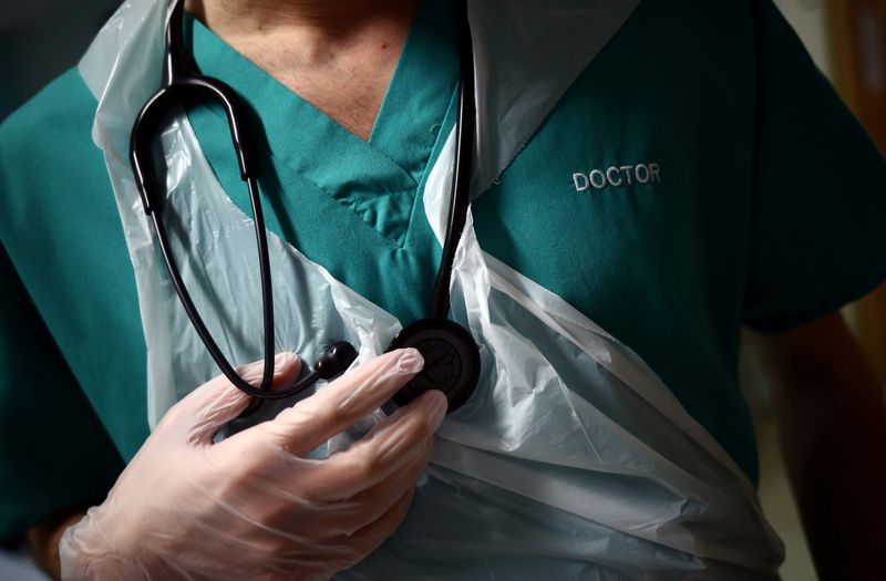 A Junior Doctor holds his stethoscope during a patient visit on Ward C22 at The Royal Blackburn Teaching Hospital in East Lancashire, following the outbreak of the coronavirus disease (COVID-19), in Blackburn, Britain, May 14, 2020. Picture taken May 14, 2020. REUTERS/Hannah McKay/Pool