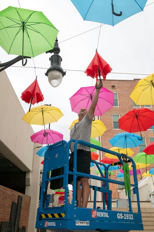 Jared Petticrew Razors Edge Designs hangs umbrellas over the alleyway between the Jefferson Street Parking Garage and the Palafox Street Businesses on June 3, 2026. The art installation is a reimagining of the beloved umbrellas that first appeared in Pensacola in the fall of 2017 as part of a Foo Foo Festival.