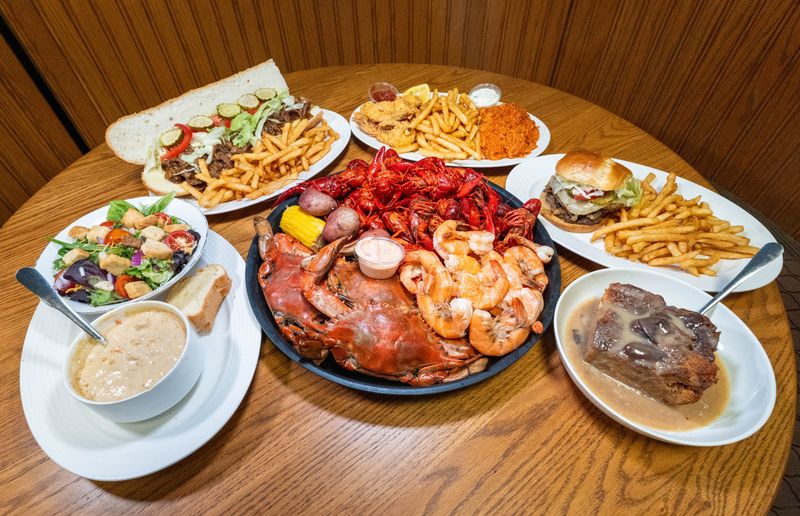 Clockwise from left, Shrimp, Crab & Corn Seafood Chowder with a side salad, a Debris Roast Beef Po’ Boy, a Fried Shrimp Platter with seafood dressing, a Cajun Blaze Burger, homemade Bread Pudding, and a Seafood Extravaganza at Coastal Cajun Cuisine in Pensacola on June 3, 2026.