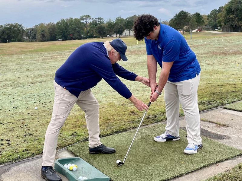 Duke Butler III helps Lucas Pedrianes of Jacksonville during a lesson at the Brentwood Golf Club. Butler was inducted into the North Florida Section PGA at a recent banquet in Orlando.