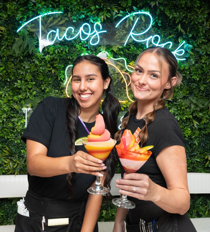Servers Nathaly Manchego, left, and Carmen Hicks hold mango/strawberry swirl soft-serve margaritas at Tacos Rock in Gulf Breeze on June 8, 2026.