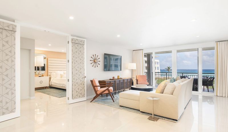 Floors in the condo are covered in large-format tile. The primary bedroom can be seen through the double doors.