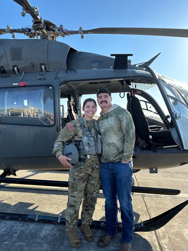 Emma Rodriguez and Jacob Rodriguez pose in front of a Black Hawk helicopter on her U.S. Army base in Fort Riley, Kansas.