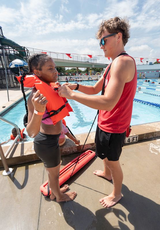 Lifeguard Brock Prindle, right, secures a life vest on Sy’niya Blackmon, 12, at the Cecil T. Hunter Pool in Pensacola on June 12, 2026.