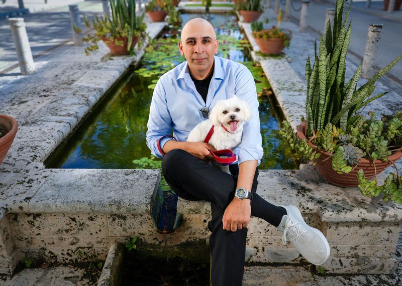 Eddie King, who has launched the online luxury dog fashion house Chloe King London, holds his 7-year-old Maltese, Chloe, at the Hibiscus Fountain near Worth Avenue.