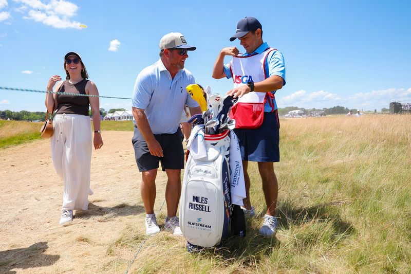 Joe Russell (L), father of Miles Russell, switches with caddie Ramon Bescansa (R) at the 18th hole during the final round of the U.S. Open on Sunday. It was Miles' Father's Day present to his dad, who walked with his son to the 18th green.
