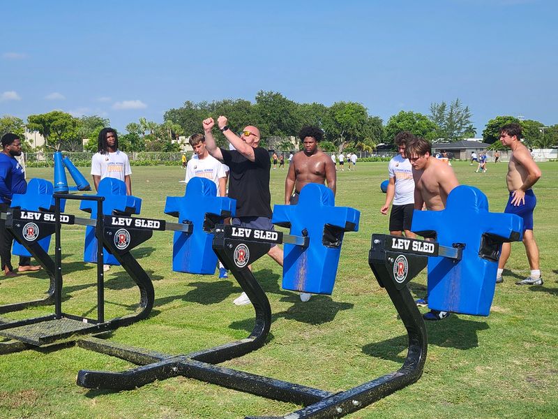 Seattle Seahawks coach Chris Partridge demonstrates lineman technique during a practice guest appearance on June 24, 2026.