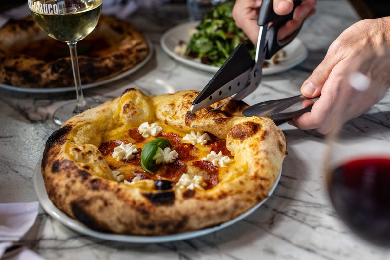Pizzas at Piccolo Buco are presented tableside and cut with scissors instead of traditional pizza cutters.
