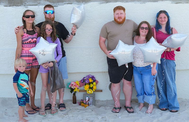 Members of the Braly family stand next to a memorial to Elizabeth Braly, on June 24, 2026, at the Dunlawton Avenue beach ramp in Daytona Beach Shores. Elizabeth, the matriarch of the family, was killed 12 years ago when a drunk driver plowed through the beach ramp's tollbooth and gate.