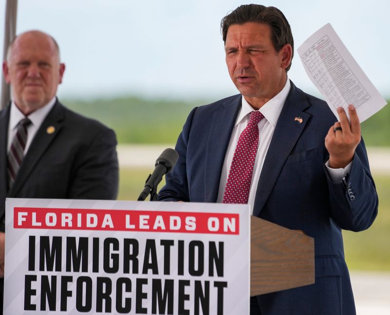 Governor Ron DeSantis holds up a sheet with crimes committed by detainees during a press conference at Alligator Alcatraz in Ochopee, Fla., on Thursday, June 25, 2026.
