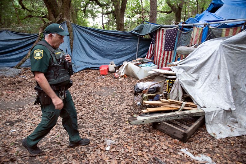 An Escambia County Sheriff's Deputy searches a homeless camp in a wooded area in the Montclair area for trespassers on June 25, 2026.