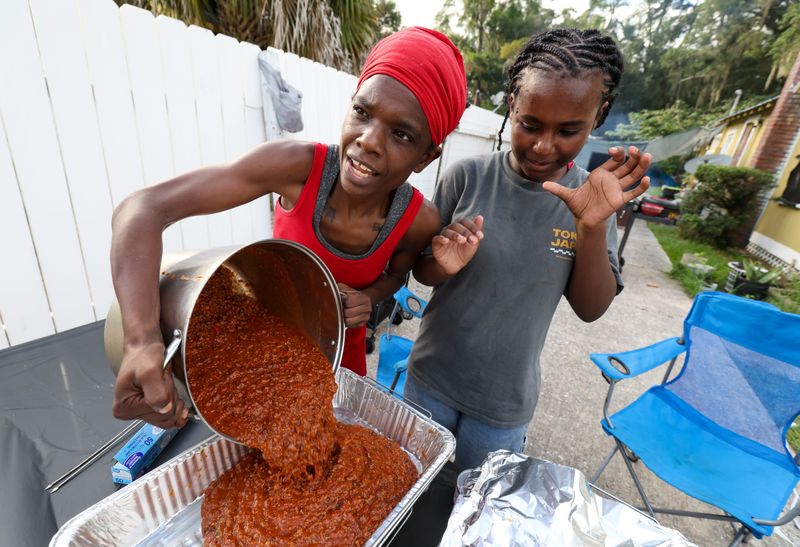 Ashlee Graves and her daughter Ambriel bring out the chili as they prepare to hand out hot meals at their home on East University Avenue in Gainesville on Thursday, June 25, 2026. For several months, the family has been cooking and serving free food to anyone who stops by a few days a week, relying on donations and often paying out of pocket.