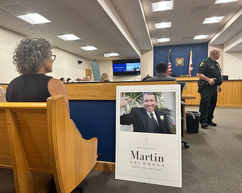 Lori Drummond sits next to a photo of her late husband, Martin Drummond, during a sentencing hearing June 26, 2026, for Elise Elder, who fatally struck Martin Drummond with her vehicle in 2024.