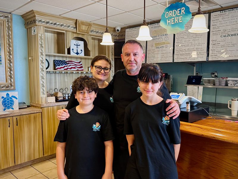 Hope (back left) and Akim Zendeli pose for a photo with their two children inside the family's new Port Orange restaurant, Zen Pizza.