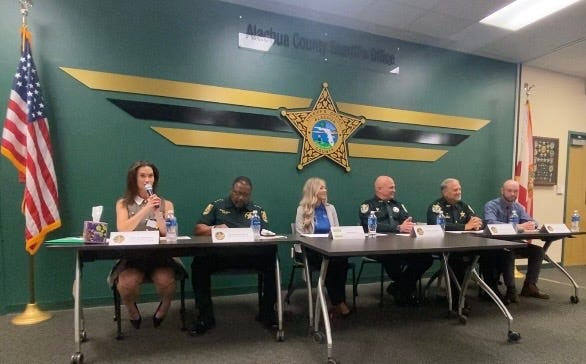 Alachua County Sheriff's Office spokesperson Lisa Sacaccio, from left, Sheriff Chad Scott, Elder Options Elder Abuse Project Coordinator Leslie Andrews, Deputy Cary Gallop, Capt. Steve Maynard and Detective Travis Parsons, are shown July 14, 2026, during a scam prevention press conference.