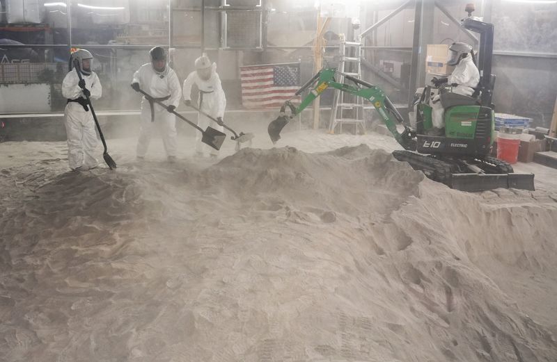 In a nondescript cluster of warehouses near the University of Central Florida campus, undergraduate students work in the 10-by-10-meter Exolith Lab under the guidance of Dan Britt, Pegasus Professor of Astronomy and Planetary Sciences. Wearing protective suits and respirators, students use shovels and an excavator to replicate moon-base infrastructure site work using simulated lunar regolith at the Oviedo lab.