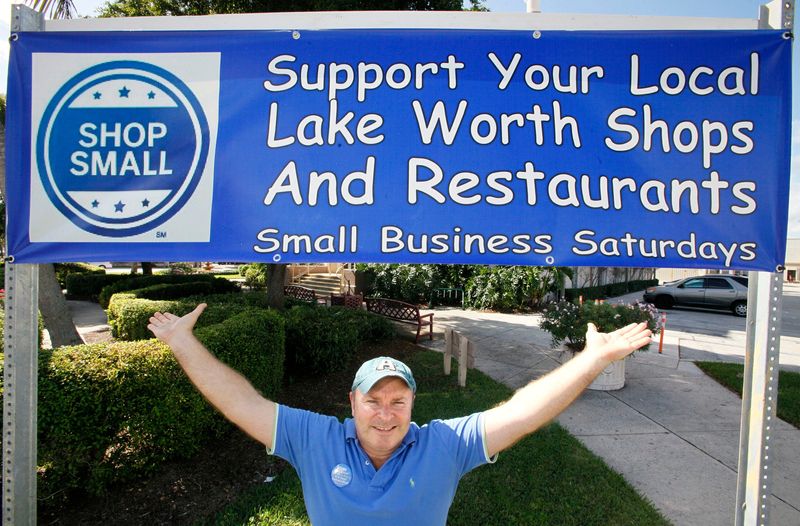 Lake Worth city commissioner Andy Amoroso stands under a banner in front of city hall promoting Small Business Saturday  on Nov. 23, 2011.